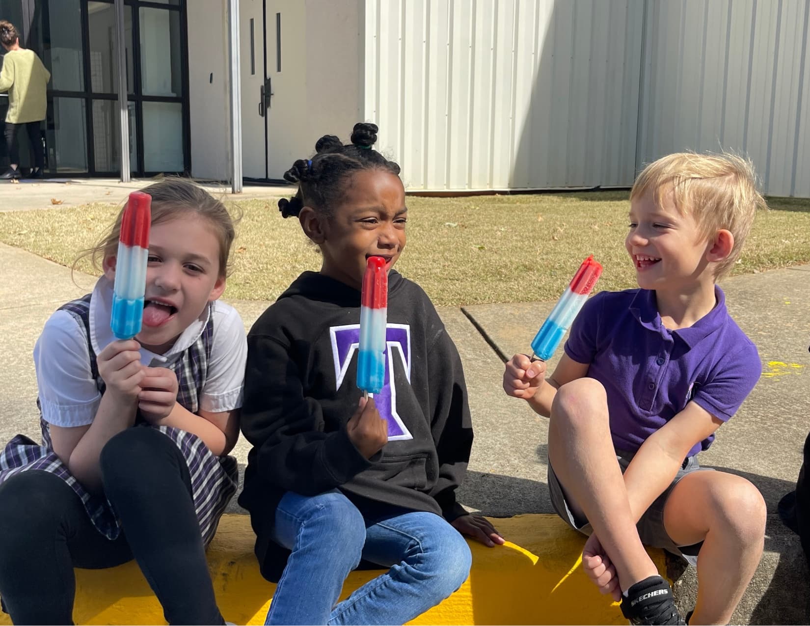 Three young TCS students laughing together outdoors