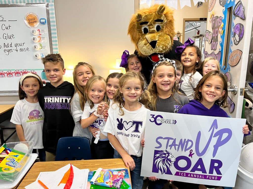 Lower-school TCS students gathered with their mascot in a classroom