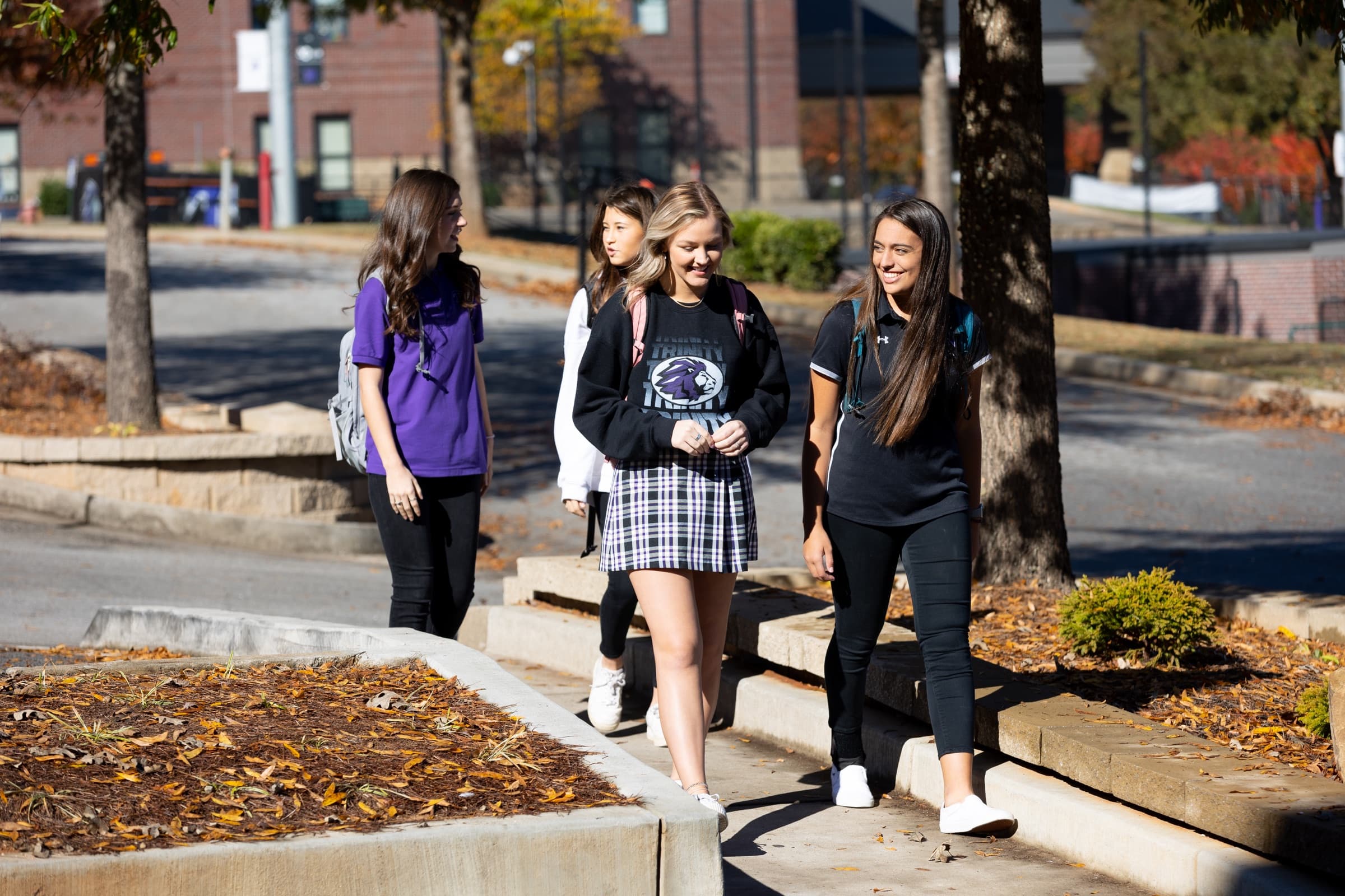 Older TCS students and a faculty member smiling as they walk across campus