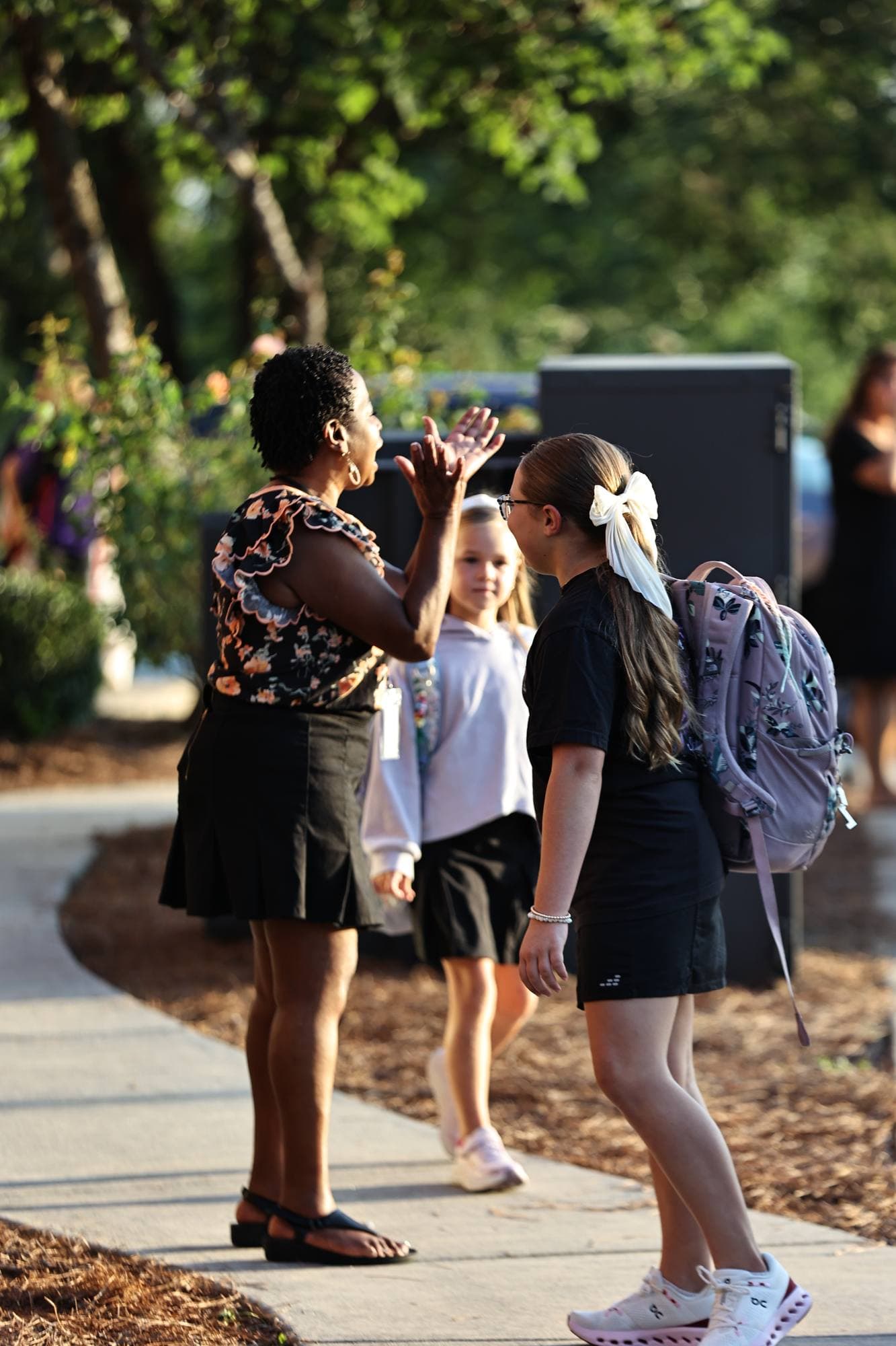 A TCS staff member high-fiving a student arriving on the campus walkway