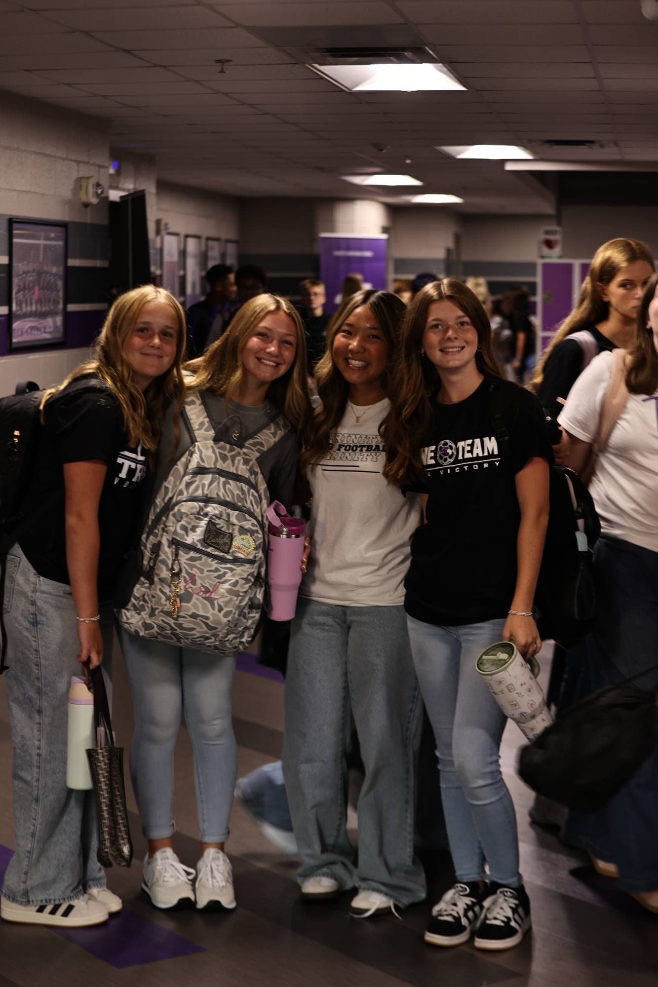 Four TCS students smiling together in a hallway on the first day back