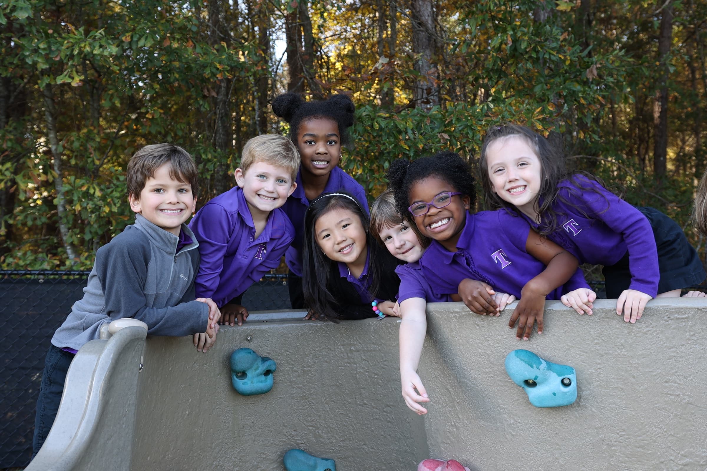 A diverse group of smiling TCS students gathered on the playground